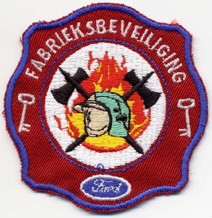 Genk (Ford) - Distintivo rosso con al centro elmo su sfondo di fiamme e simbolo e dicitura Ford