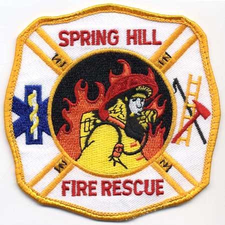 Spring Hill - Distintivo bianco con al centro pompiere su sfondo di fiamme