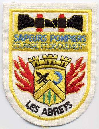 Les Abrets - Distintivo bianco con al centro torri e fiamme