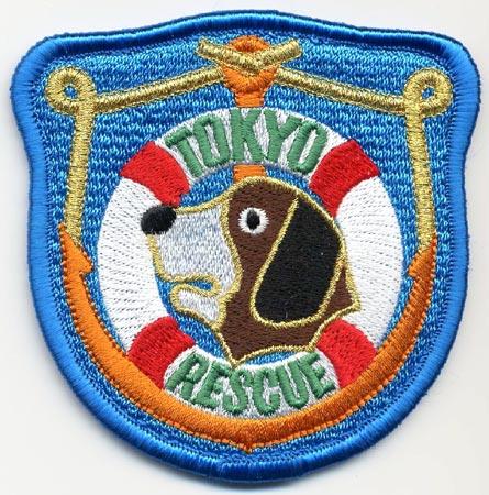 Tokyo - Distintivo azzurro con al centro un cane e un salvagente
