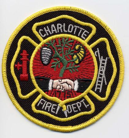 Charlotte - Distintivo nero con al centro due mani che si stringono su sfondo rosso