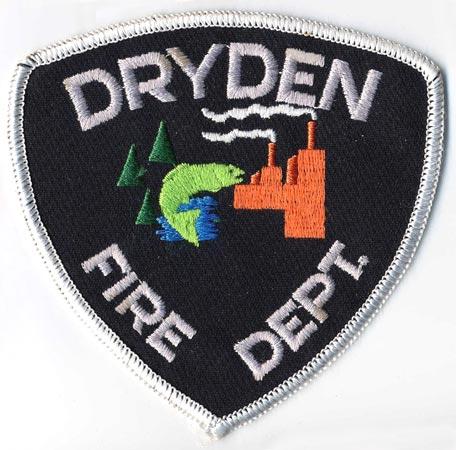 Dryden - Distintivo nero con al centro un pesce una fabbrica e degli alberi