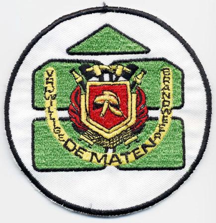 De Maten - Distintivo bianco e verde con al centro un elmo su sfondo rosso